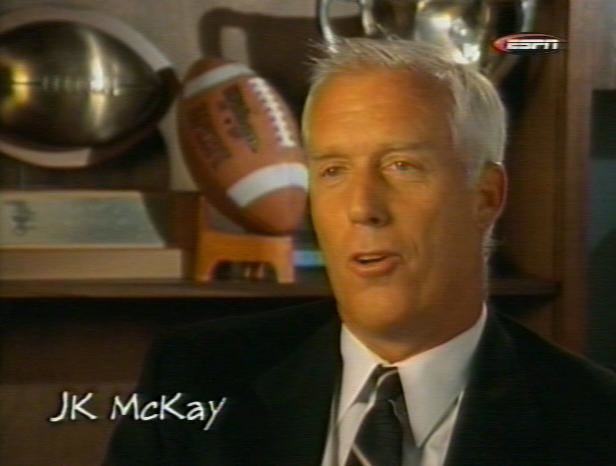 John McKay, Jr. with white hair and wearing a suit and a tie during an interview.