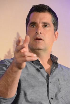 John Newton (actor) doing hand gestures wearing a gray long-sleeved shirt