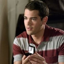 Jesse Metcalfe proposing with a ring while wearing a red and white stripe shirt