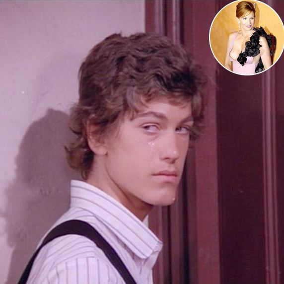 Jonathan Gilbert looking at something with a serious face and curly hair while wearing a white striped polo and black suspenders in a scene from the 1974 TV Series, Little House on the Prairie. Melissa Gilbert is in the upper right corner smiling with brown tied-up hair wearing a pink and black dress with a plunging neckline that exposes her cleavage