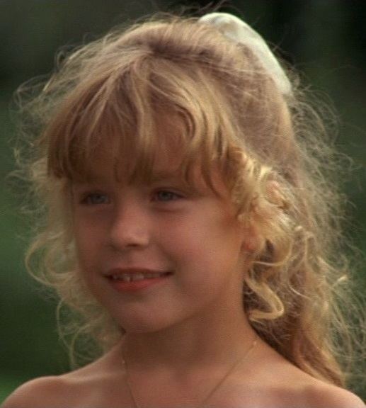 Young Jonna Liljendahl smiling with blonde curly hair and wearing a necklace