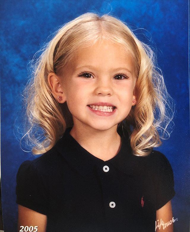 Young Jordyn Jones smiling with blonde curly hair while wearing a black blouse