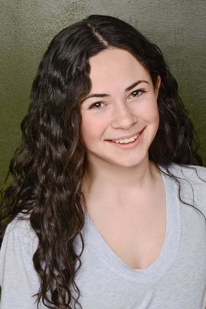 Jordyn Negri smiling, with her curly hair down, and wearing a gray blouse.