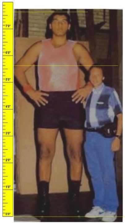 Jorge González looking serious with hands on hips and his height  measurement compared to the man standing next to him