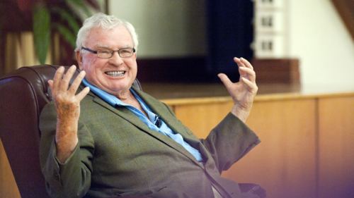 Joseph A. Hardy III wearing green coat and blue long sleeves while smiling