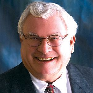 Joseph A. Hardy III wearing eyeglasses, black coat, white long sleeves and neck tie while smiling