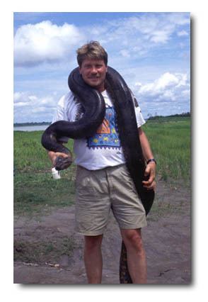 Joseph Bruno Slowinski smiling while carrying a black big snake around his neck