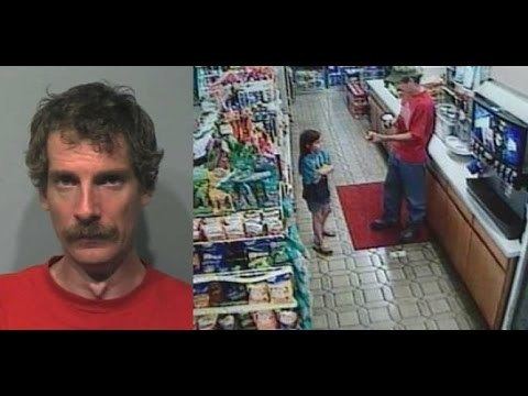 Joseph Edward Duncan III (right) is serious, has black curly hair, a mustache, and wears a red shirt. Shasta Groene (middle) inside a convenience store, has long blonde hair, her arms crossed, and wears a green-black shirt, gray shorts, and black slippers. Joseph Edward Duncan III (right) is serious while at the counter, left-hand handing something to Shasta, and his right-hand holding a cup, wearing a gray cap, red shirt, denim pants, and black shoes.