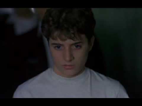 Joseph Perrino looking at something with a serious face in a scene from the 1996 American legal crime drama film, Sleepers while wearing a white t-shirt.