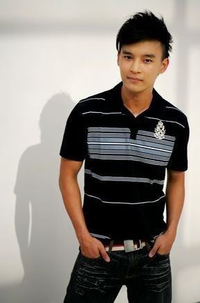 Joshua Ang with a tight-lipped smile while hands on his pocket and wearing a black and white striped polo shirt and denim pants