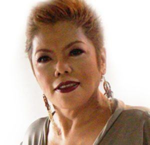 Joy Viado smiling and wearing a gray blouse with dangling earrings