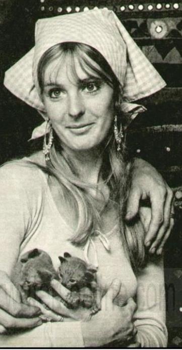 Judith Trim smiling while carrying kittens and wearing a checkered bandana and blouse