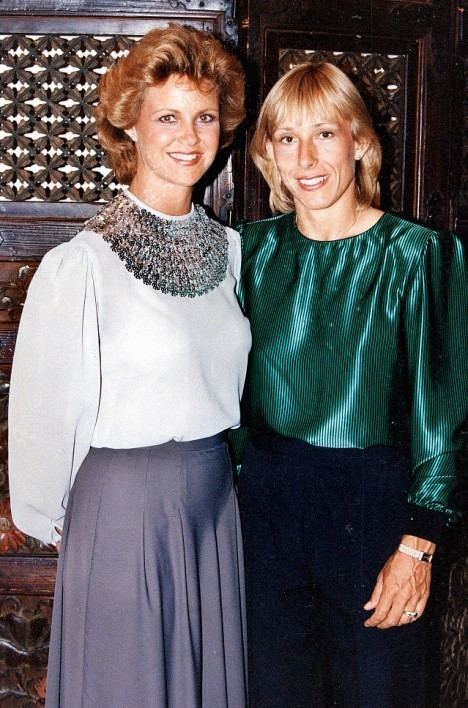 Judy Nelson smiling and wearing white blouse and blue skirt while Martina Navratilova smiling and wearing green blouse
