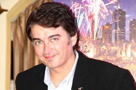 Jugal Hansraj smiling while wearing a black coat and white long sleeves