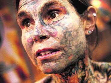 Julia Gnuse wearing piercings and covered her whole face and neck with tattoos.