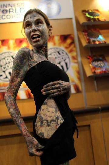 Julia Gnuse wearing a black top, black shorts and covered her body with tattoos.