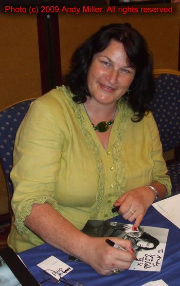 Julie T. Wallace signing autograph while wearing yellow blouse