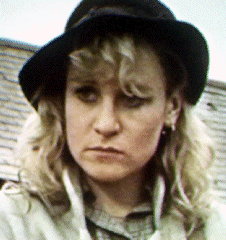 Juliet Hammond-Hill looking afar while wearing a black hat and checkered blouse