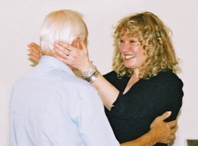 Juliet Hammond-Hill smiling while greeting Clifford Rose and wearing a black long sleeve blouse, ring, and bracelets