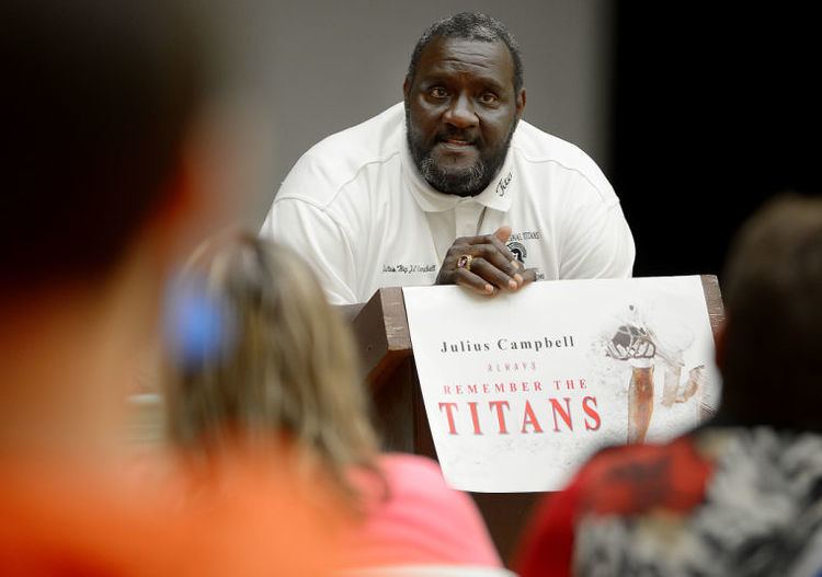 Julius Campbell talking in front of many people while wearing a white shirt