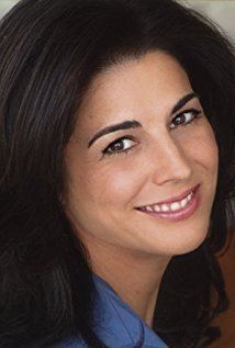 Justine Miceli smiling while wearing a blue blouse