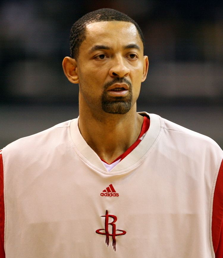 Juwan Howard looking serious with a beard and mustache while wearing a red and white jersey with the word "Adidas" written on it