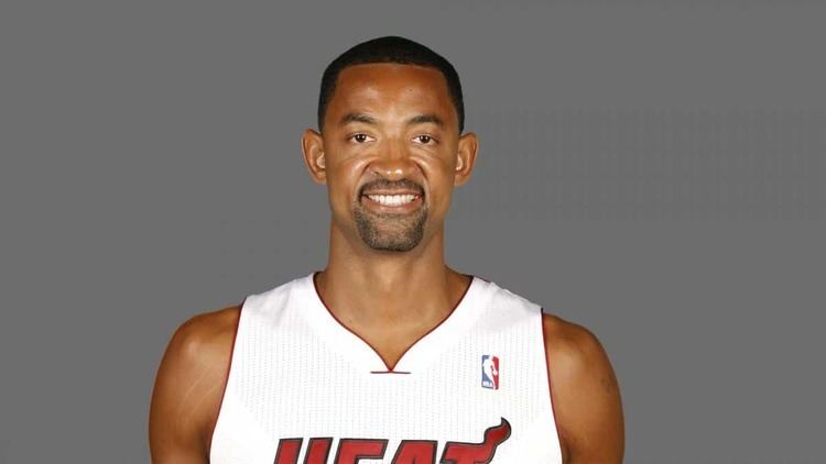 Juwan Howard smiling with a beard and mustache while wearing a white  jersey with the word "HEAT" & the NBA logo written on it