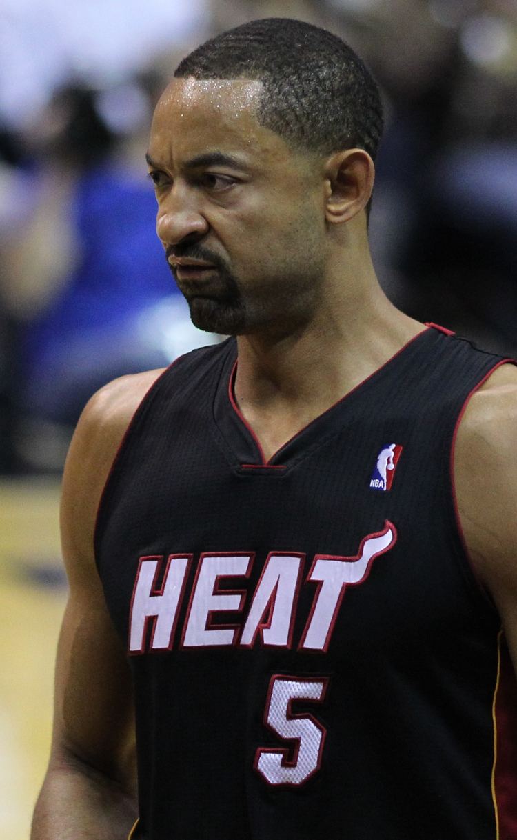 Juwan Howard looking serious and wearing a black jersey with the word "HEAT", the jersey number "5" and the NBA logo written on it