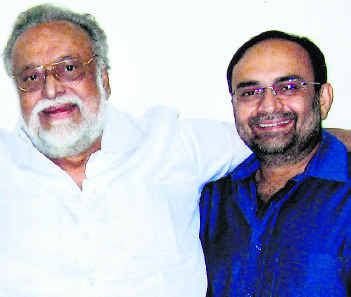 K Balaji wearing eyeglasses and white long sleeves while smiling with a man beside him wearing blue long sleeves and eyeglasses