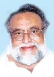 K Balaji wearing eyeglasses and white long sleeves while smiling