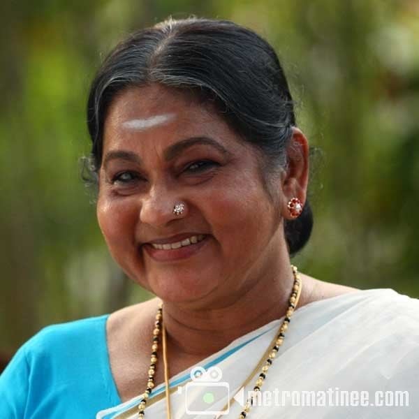 K. P. A. C. Lalitha smiling while wearing a blue blouse, white dupatta, nose-jewel, necklace, and earrings