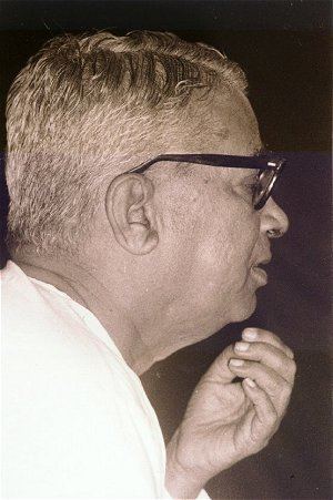 K. S. Narasimhaswamy looking serious in a side view while wearing eyeglasses and a white shirt