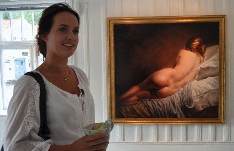 Kaja Norum smiling while wearing white blouse and beside her is the painting 'Molly'