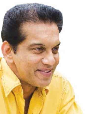 Kamal Addararachchi smiling while wearing yellow long sleeves