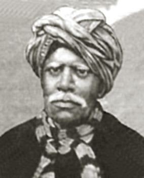 Kandukuri Veeresalingam with a serious look, having a white mustache wearing a turban, black & white scarf & balck shirt