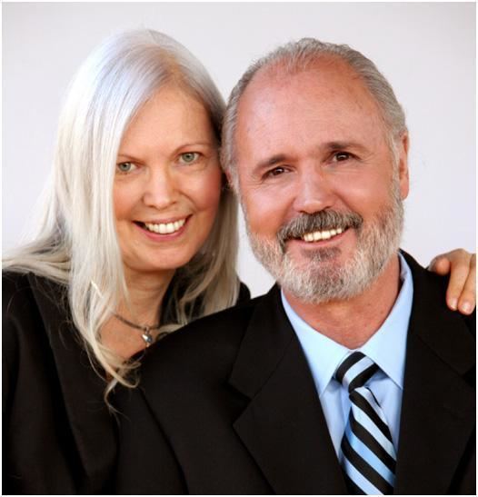 Karen Zerby smiling with her husband, Steven Douglas Kelly and wearing a black dress and a necklace.