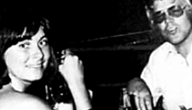 Kari Storækre and Arne Treholt are smiling while Kari is holding a bottle and Arne is wearing eyeglasses and long sleeve