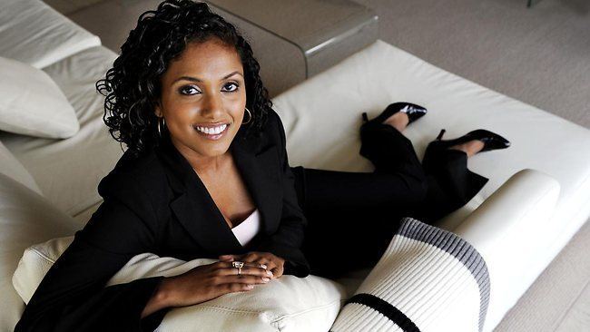 Karina Carvalho wearing formal attire sitting on the sofa
