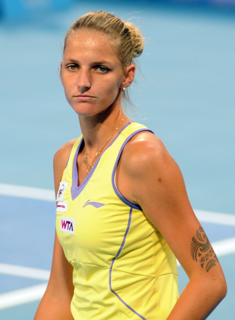 Karolína Plíšková with a serious face and wearing a yellow-green sleeveless top with a tattoo on her arm.