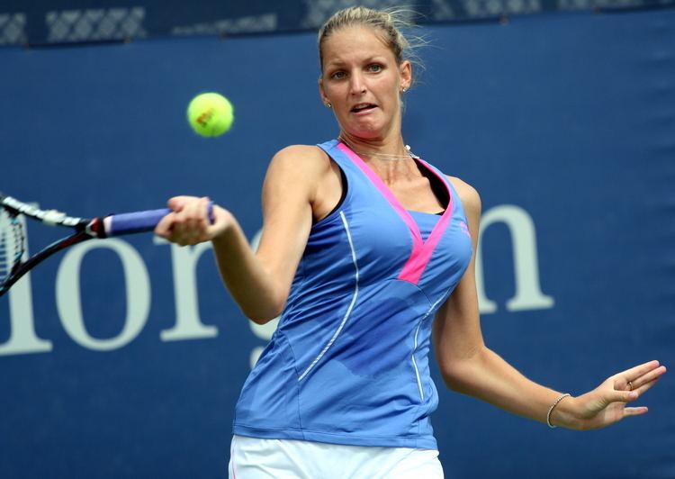 Karolína Plíšková wearing a blue sleeveless top and white skirt while playing tennis.