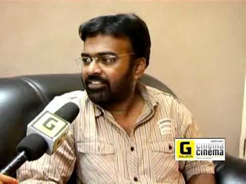 Karu Pazhaniappan in one of his interviews wearing eyeglasses and beige stripped long sleeves