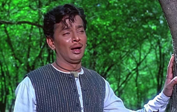 Kashinath Ghanekar crying, wearing earrings, a necklace, white long sleeves, and striped chalico.