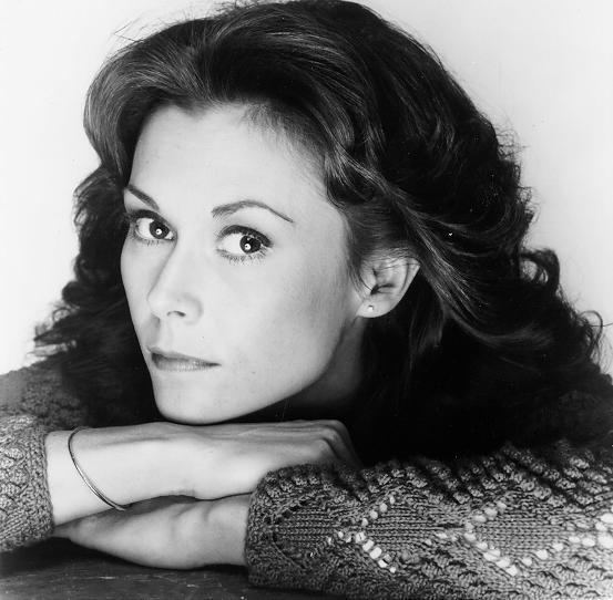 Kate Jackson with wavy hair and wearing a crochet long sleeve top and bracelet