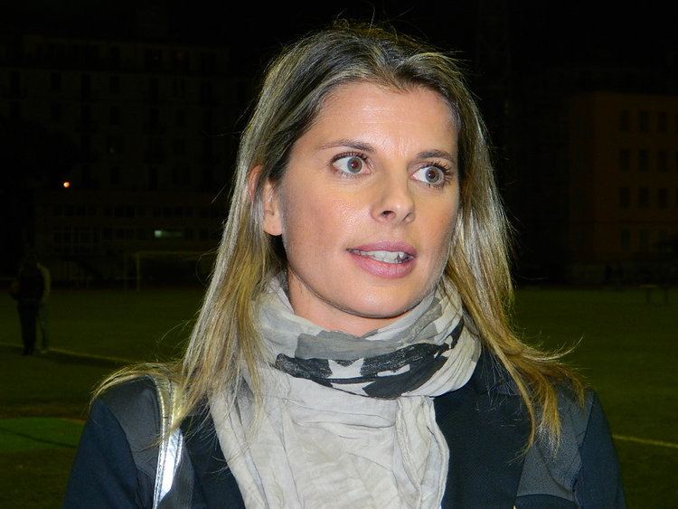 Katia Serra with her blonde colored hair wearing a scarf and a long-sleeved shirt