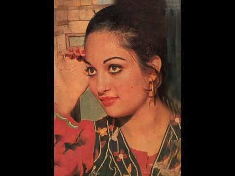 Kaveeta with a tight-lipped smile while looking at something and wearing a black and red floral blouse