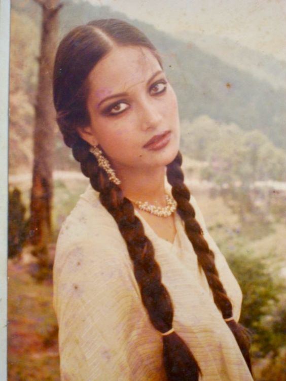 Kavita with braided hair while wearing a light yellow blouse, earrings, and necklace