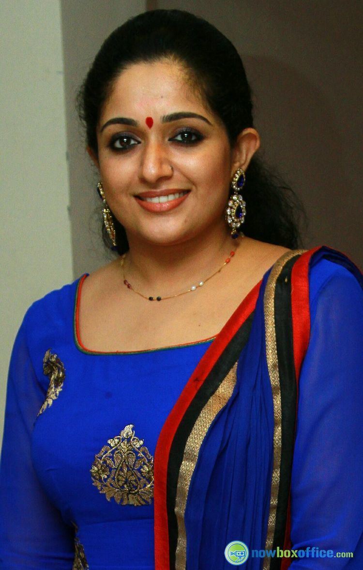 Smiling Kavya Madhavan wearing earrings and a blue dress