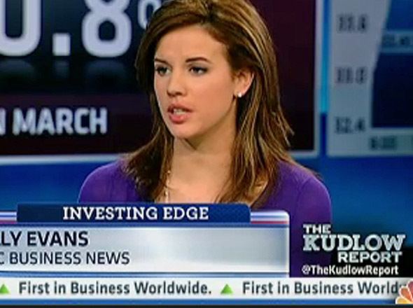 Kelly Evans with serious face while reporting on CNBC TV and wearing a purp...