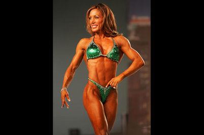 Kelly Ryan, a fitness model, wears a green two-piece bikini while walking on stage