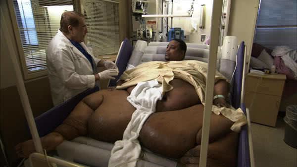 Kenneth Brumley lying in a hospital bed and talking to a doctor.